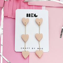 Load image into Gallery viewer, Clay neutral beige three tiered heart earrings w/ Gold filled earring components; handmade in Charlotte, NC.