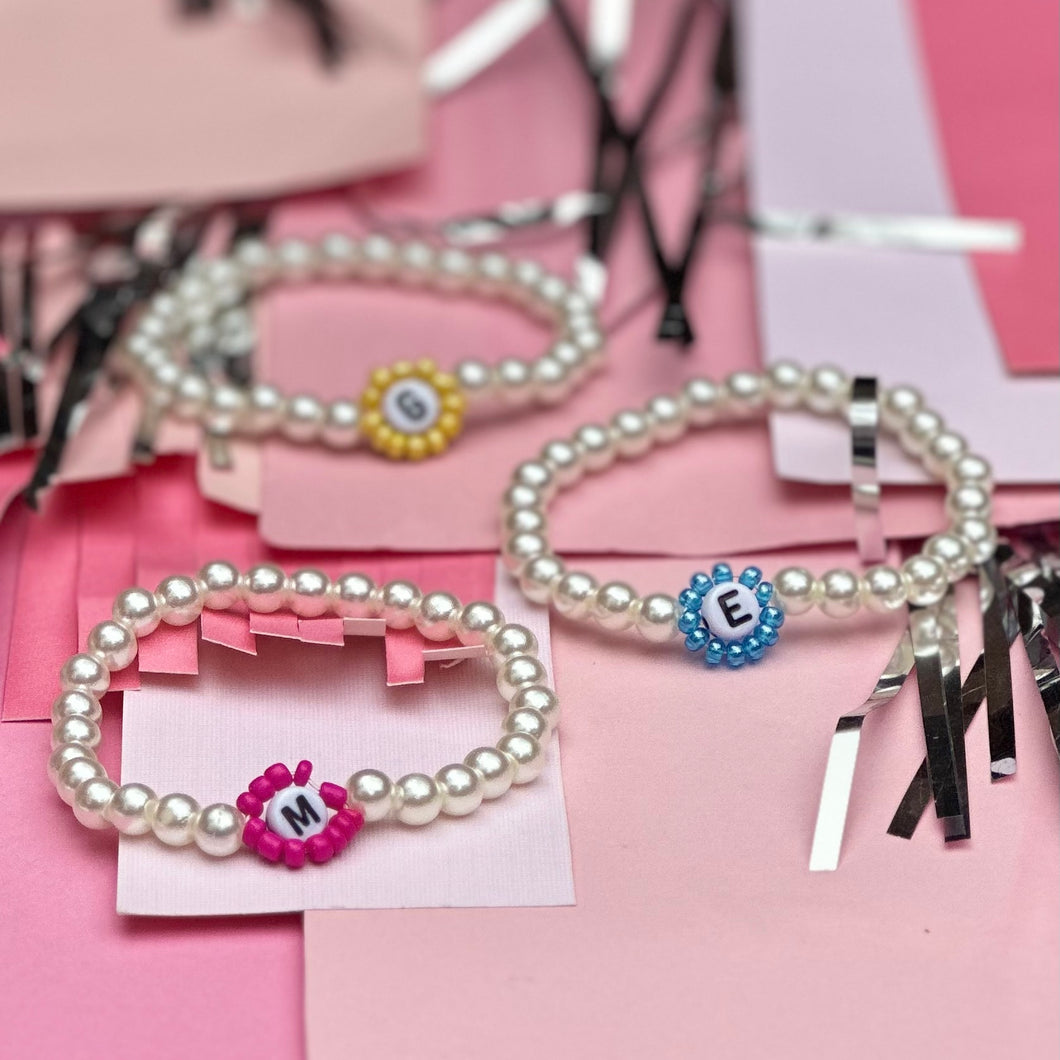 Customizable monogram stretch bracelet - made of imitation pearls and a letter of the alphabet surrounded by small colored beads. The bracelet letter & colors are customizable and they are handmade in Charlotte, NC.